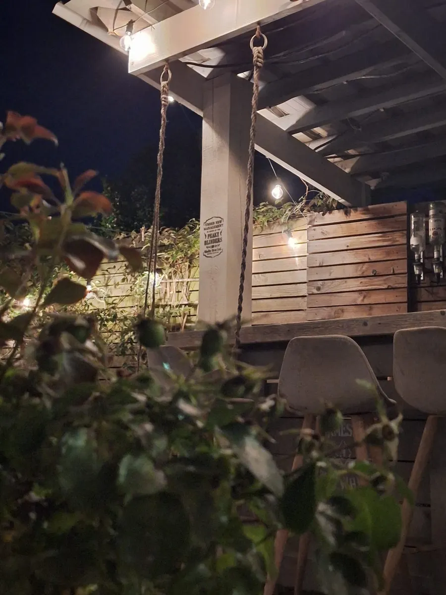 Timber outdoor bar seen through soft-focus foliage at night