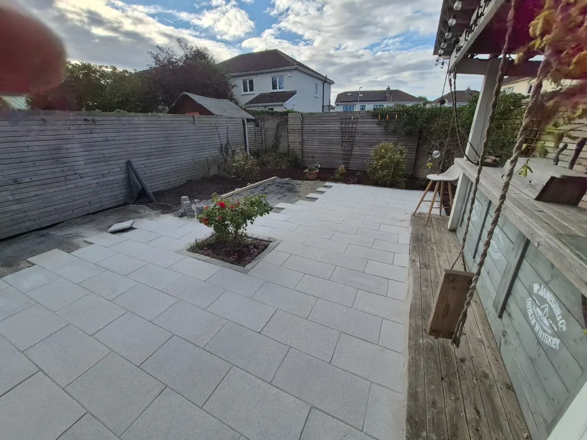 Finished porcelain patio seen from the house, with a rose bed, timber bar and fenced back garden