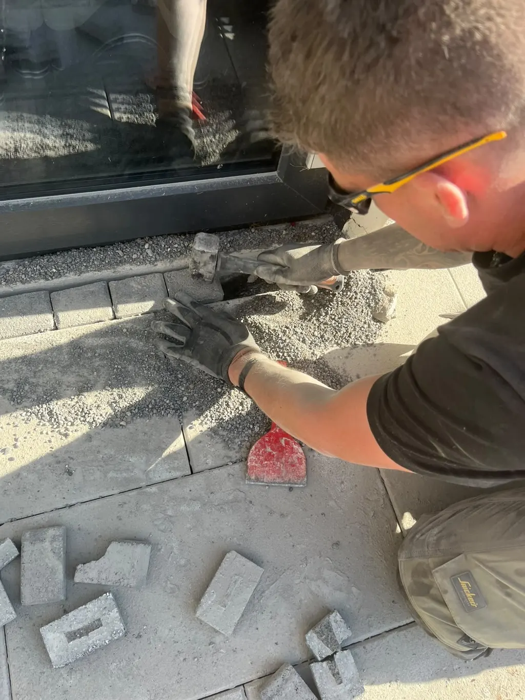 Setting a paving sett along the patio edge by hand, with safety glasses on