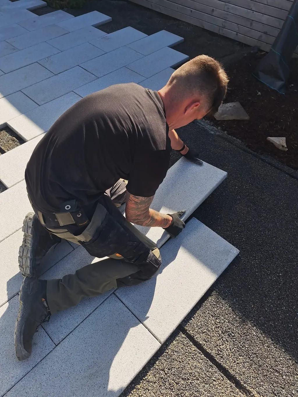 Seanie’s crew setting a long porcelain plank into a stepped patio layout