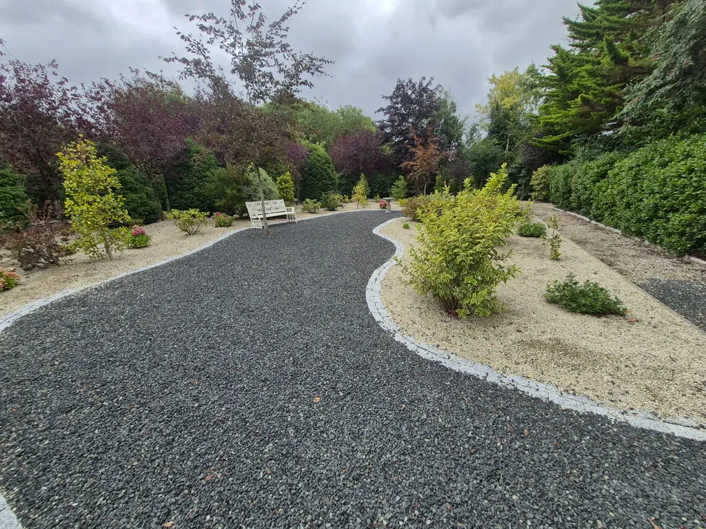 Curving dark gravel path edged with granite setts through planted gravel beds, a finished Kildare Plant & Garden job